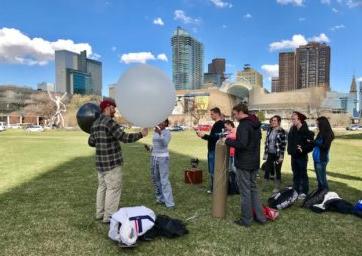 Students preparing to launch a weather balloon from a campus greenspace