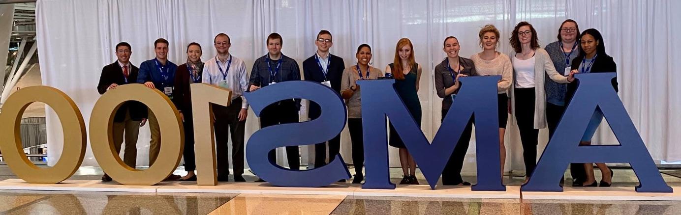 Students posing in front of the AMS 100 sign at AMS Boston in 2020