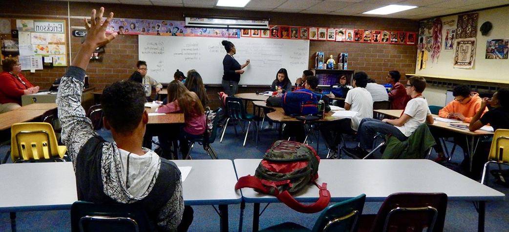 Photograph of a teacher instructing children in a classroom.